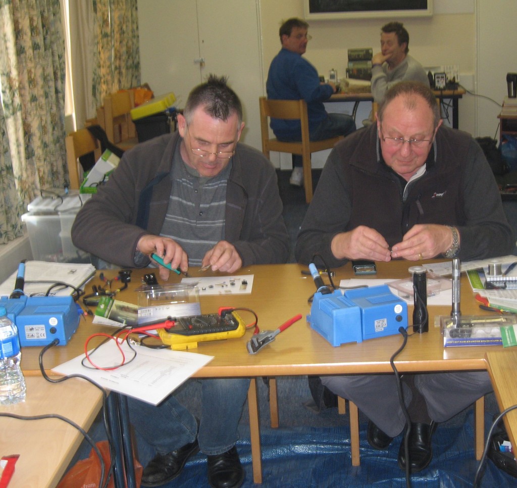 Andy xxxx and David busy building their Signal Generator kits.  In the background (L to R) Ron G6LTT and Derek M0XDC)